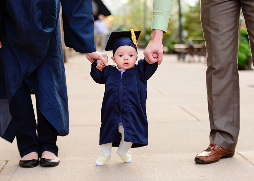 Baby wearing graduation gown and cap